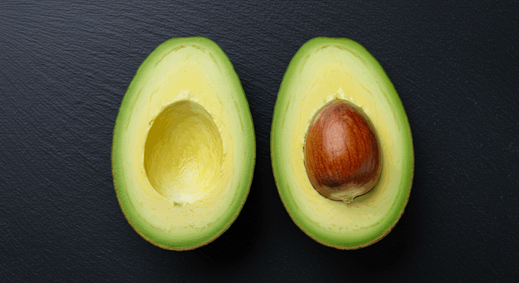 Prompt: A perfectly ripe avocado sliced cleanly in half, with one half containing the smooth, brown pit. The two halves rest on a dark slate background, symbolizing balance (like a yin-yang). The vibrant green flesh is perfectly textured and inviting. Photographed from top-down, beautiful natural lighting, balanced composition. 